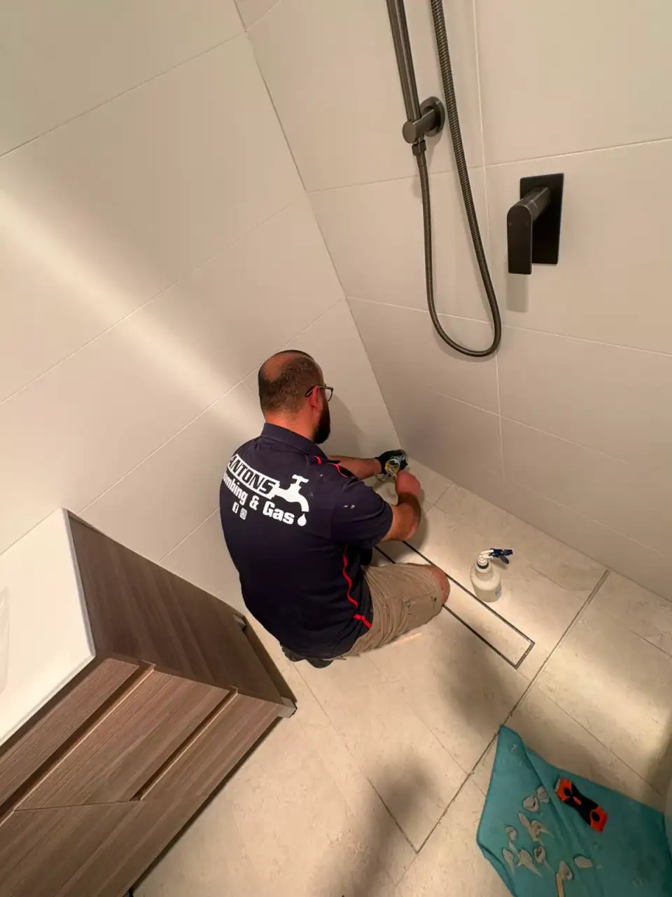 Licensed plumber completing a bathroom floor-drain repair