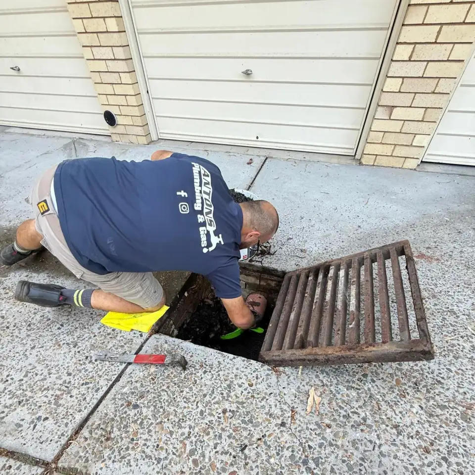 Drain plumber working inside an open outdoor drain pit