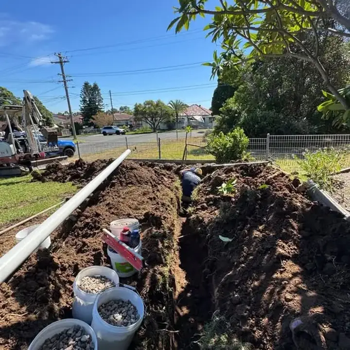 Open drainage trench with pipe and excavation materials beside it