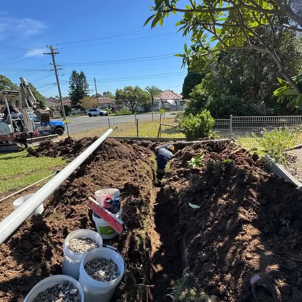 Open drainage trench with pipe and excavation materials beside it